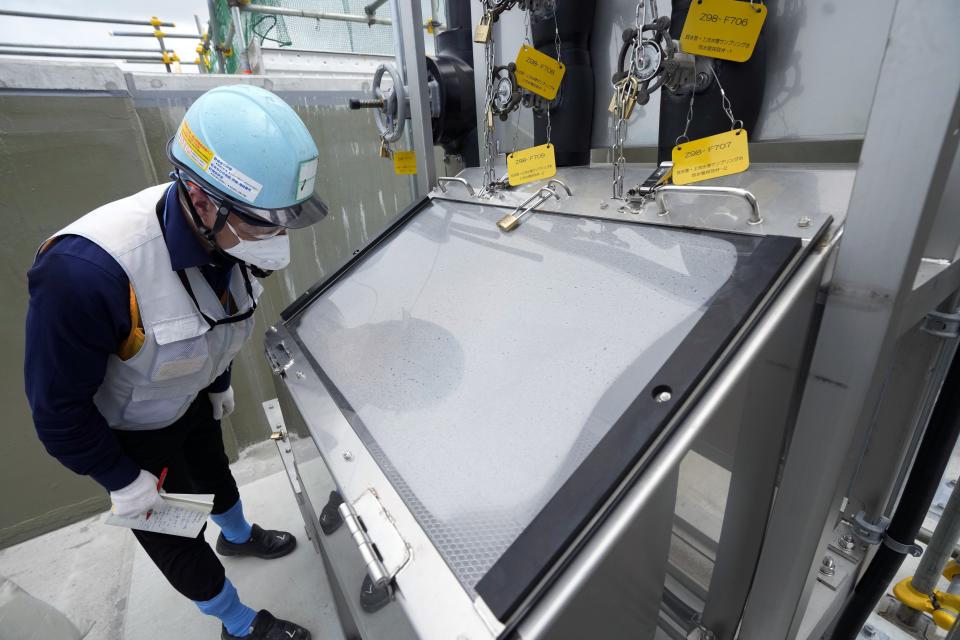 This photo taken during the tour of the treated water dilution and discharge facility for foreign media shows a journalist looks at the water sampling rack, part of the facility for the releasing treated radioactive water to sea from the Fukushima Daiichi nuclear power plant, operated by Tokyo Electric Power Company Holdings (TEPCO), in Futaba town, northeastern Japan, Sunday, Aug. 27, 2023. (AP Photo/Eugene Hoshiko, Pool)