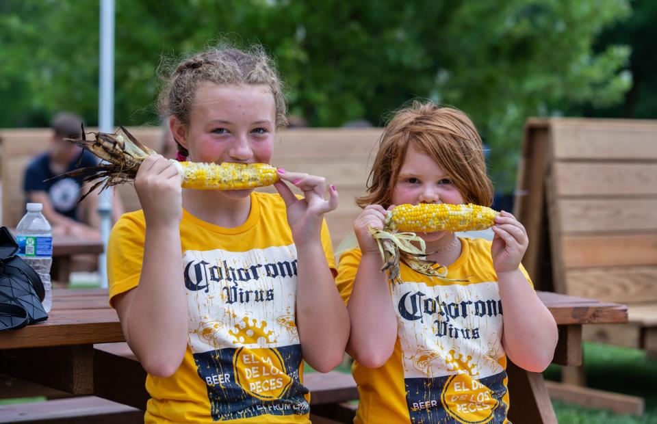 Eleven-year-old Josie Goetz and her sister Isabelle, 8, enjoy grilled sweet corn during Corn Fest at Inventors Brewpub in Port Washington July 18, 2020. Several area businesses hosted weekend events as Port Washington's annual Fish Day festivities were canceled due to COVID-19 concerns. Fish Day returns to Port Washington July 15-16, 2022.