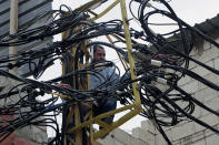 FILE - In this May 21, 2014, file, photo, Abu Wadiyeh, a 34-year-old Palestinian who was born in Syria, fixes power cables at the Palestinian refugee camp of Shatila in Beirut, Lebanon. Lebanon's energy minister said Thursday, July 16, 2020 the country's worsening economic crisis is making it increasingly difficult to attract investors for its ailing electricity sector.(AP Photo/Bilal Hussein, File)