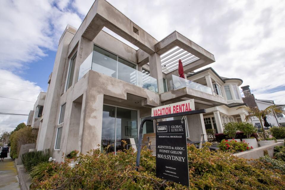 A sign at a modern beach-front home advertises that it is available for vacation rental.