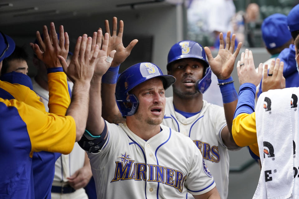 Seattle Mariners Kyle Seager, left, and Kyle Lewis are congratulated in the dugout after scoring against the Texas Rangers in the third inning of a baseball game Sunday, May 30, 2021, in Seattle. (AP Photo/Elaine Thompson)