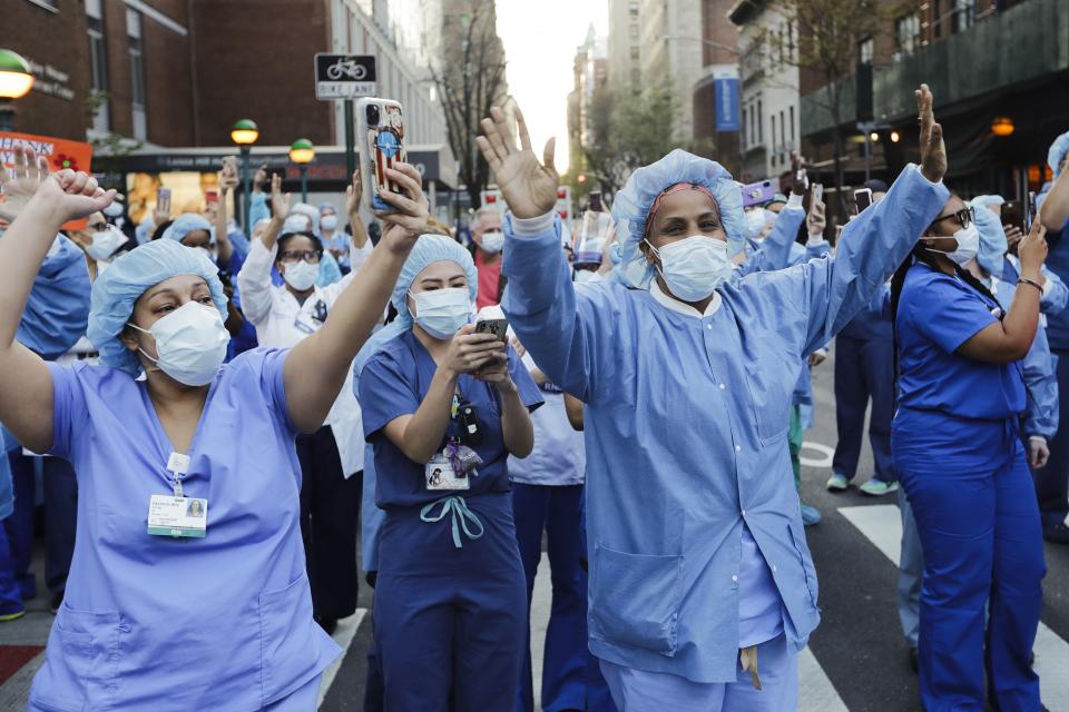 Nurses and medical workers react as police officers and pedestrians cheer them outside Lenox Hill Hospital Wednesday, April 15, 2020, in New York. (AP Photo/Frank Franklin II)