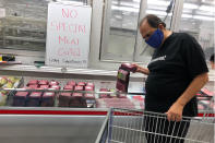 In this Tuesday, March 31, 2020 photo, comedian Frank De Lima wears a masks and maintains social distancing while shopping for ground beef at a Sam's Club store in Honolulu. People in Hawaii are changing how they express aloha in the time of coronavirus. Some residents say social distancing is the antithesis of tradition in the state, where people greet each other with hugs, kisses and lei, and families are close-knit. (AP Photo/Jennifer Sinco Kelleher)