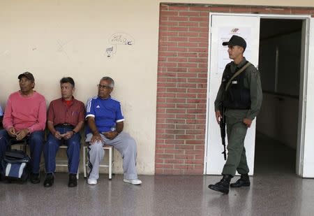 People wait to vote in a polling center as a National Bolivarian Guard stands guard in Caracas, June 28, 2015. REUTERS/Jorge Dan Lopez