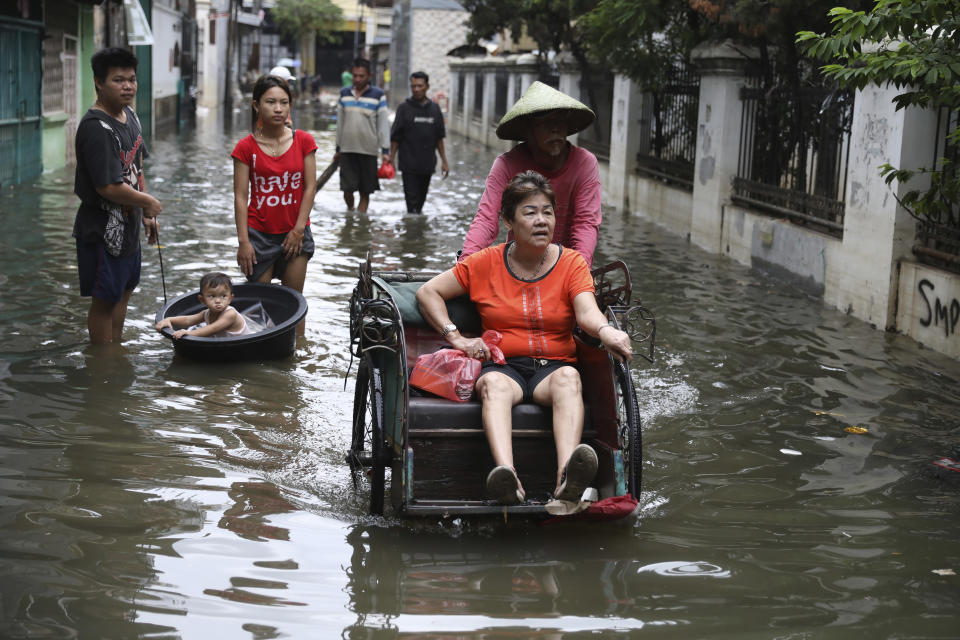 A woman rides a tricycle on a flooded street in Jakarta, Indonesia, Saturday, Jan. 4, 2020. Monsoon rains and rising rivers submerged parts of greater Jakarta and caused landslides in Bogor and Depok districts on the city's outskirts as well as in neighboring Lebak, which buried a number of people. (AP Photo/Dita Alangkara)