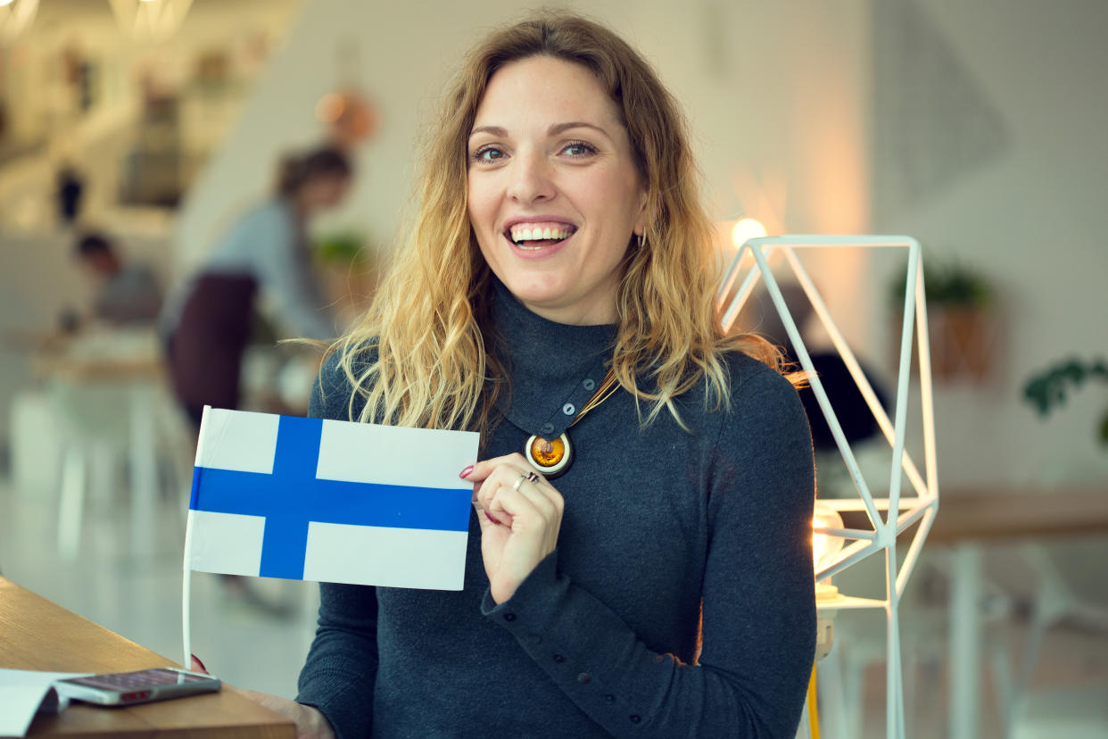 Scandinavian woman holds the flag of Finland in the background on the premises of the cafe.
