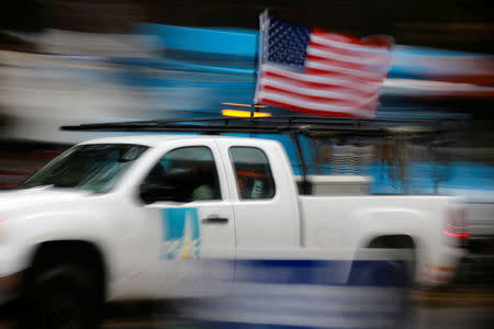 FILE PHOTO: A PG&E truck carrying an American Flag drives past PG&E repair trucks in Paradise, California, U.S. November 21, 2018. REUTERS/Elijah Nouvelage