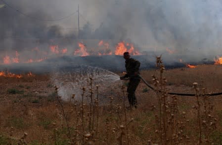 Member of the Iraqi Popular Mobilisation Forces attempts to put out a fire in the northern town of Bashiqa, east of Mosul