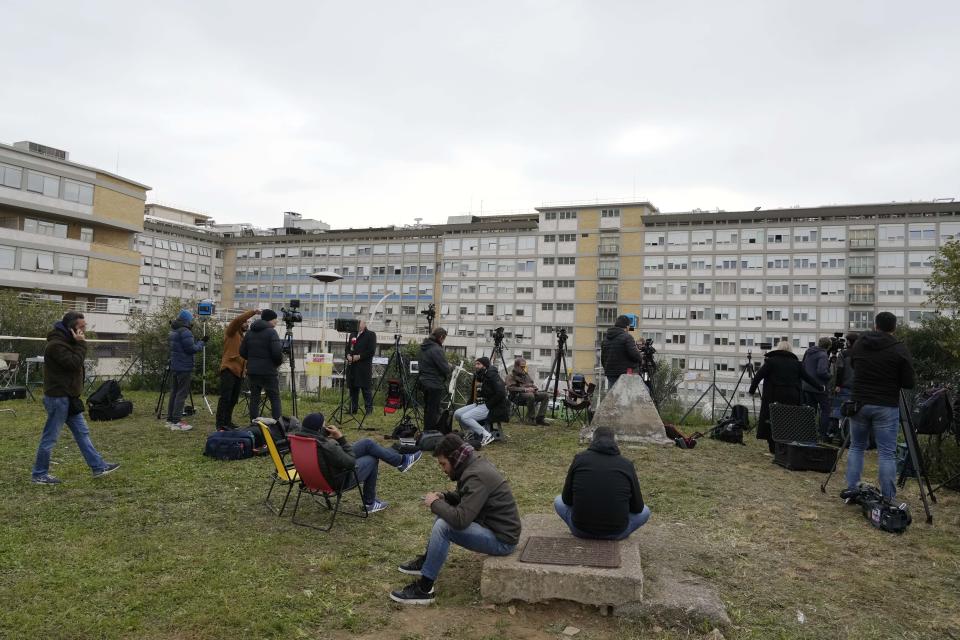 Members of the media set up their gear outside the Agostino Gemelli hospital under the rooms on the top floor normally used when a pope is hospitalised, in Rome, Friday, March 31, 2023. Pope Francis spent another night in hospital after showing a "marked improvement" Thursday and could be released from the hospital in the coming days, the Vatican and his doctors reported. (AP Photo/Gregorio Borgia)