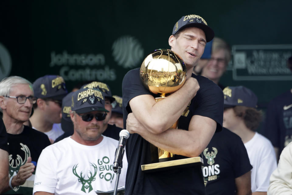 Milwaukee Bucks' Brook Lopez hugs the NBA Championship trophy during a parade celebrating the Milwaukee Bucks' NBA Championship basketball team Thursday, July 22, 2021, in Milwaukee. (AP Photo/Aaron Gash)