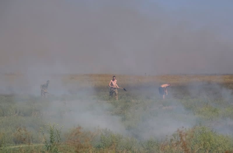 Ukrainian servicemen put out burning grass near their positions in Zaporizhzhia region