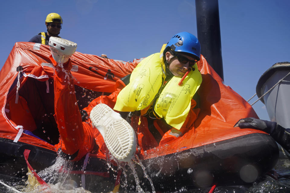 John Mansolillo helps other classmates get into a six-person life raft during a Global Wind Organisation certification class at the Massachusetts Maritime Academy in Bourne, Mass., Thursday, Aug. 4, 2022. At the 131-year-old maritime academy along Buzzards Bay, people who will build the nation's first commercial-scale offshore wind farm are learning the skills to stay safe while working around turbines at sea. (AP Photo/Seth Wenig)