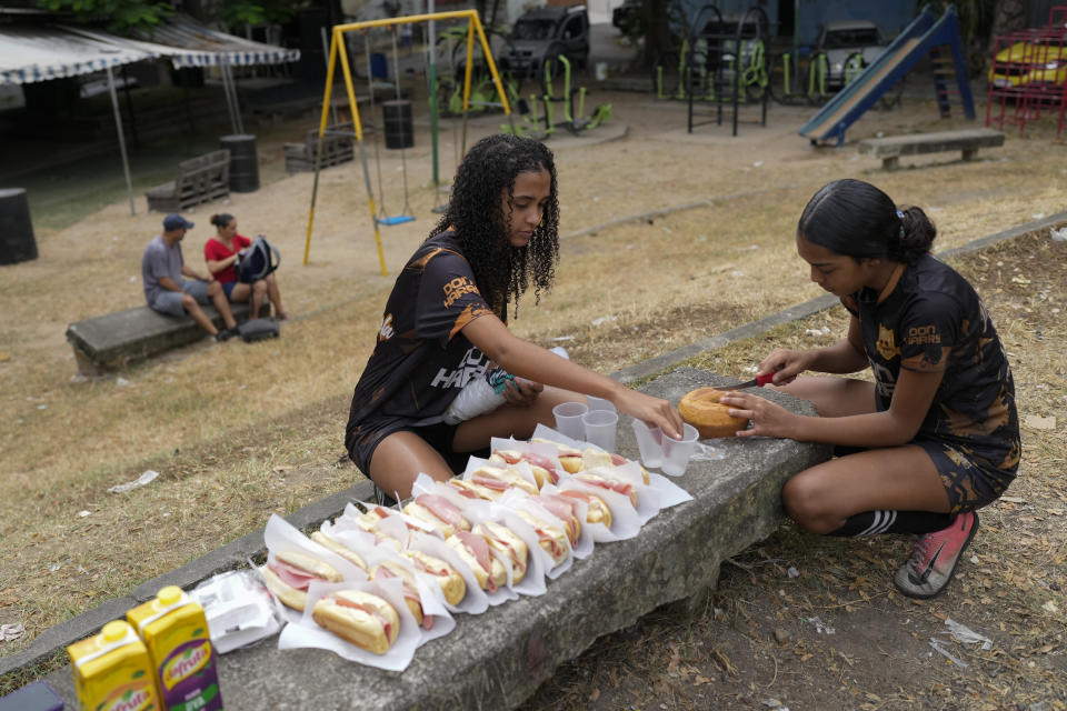 Young women ready breakfast for fellow participants as part of a soccer training session run by the Bola de Ouro social program, at the Complexo da Alemao favela in Rio de Janeiro, Brazil, Thursday, May 16, 2024. Young women are participating in soccer programs led by community trainers, where they receive both sports and personal development training. (AP Photo/Silvia Izquierdo)