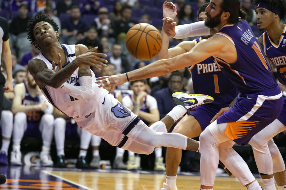 CORRECTS TO SAY THE GRIZZLIES WON, NOT THE SUN - Memphis Grizzlies guard Ja Morant (12) attempts to save the ball in front of Phoenix Suns guard Devin Booker (1), Kelly Oubre Jr. (3) and Ricky Rubio in the second half during an NBA basketball game, Sunday, Jan. 5, 2020, in Phoenix. The Grizzlies won 121-114. (AP Photo/Rick Scuteri)