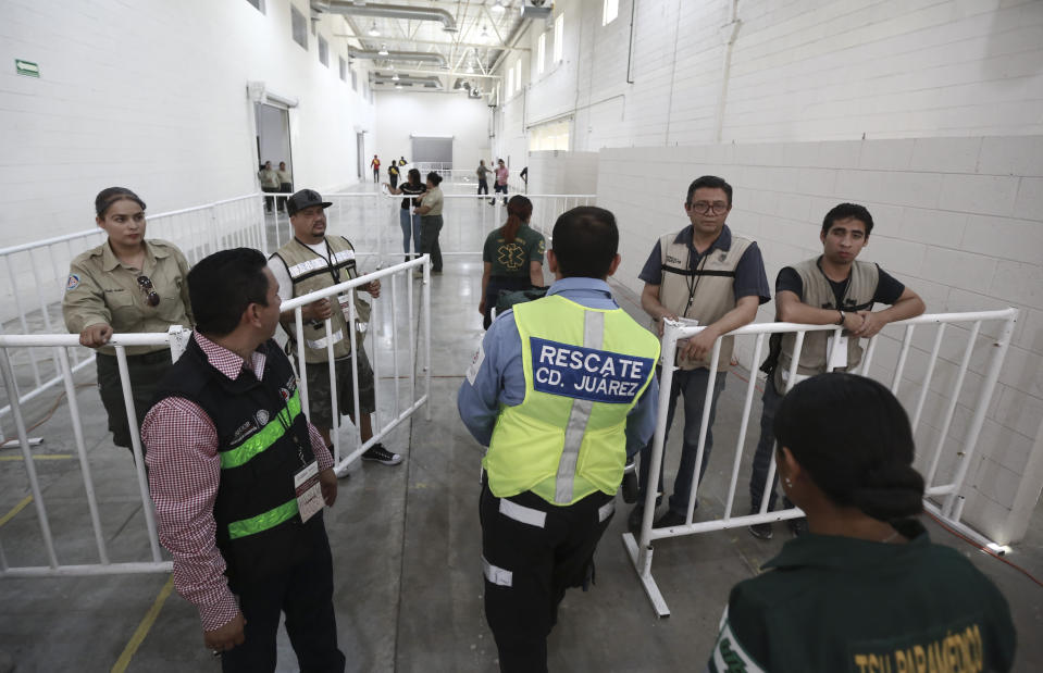 Mexican government workers walk inside the newly opened migrant shelter, formerly an assembly plant, in Ciudad Juarez, Mexico, Thursday, Aug. 1, 2019. The Mexican government opened its first shelter here to house Central American and other migrants seeking asylum in the United States who have been sent back to Mexico to await the process. (AP Photo/Christian Chavez)