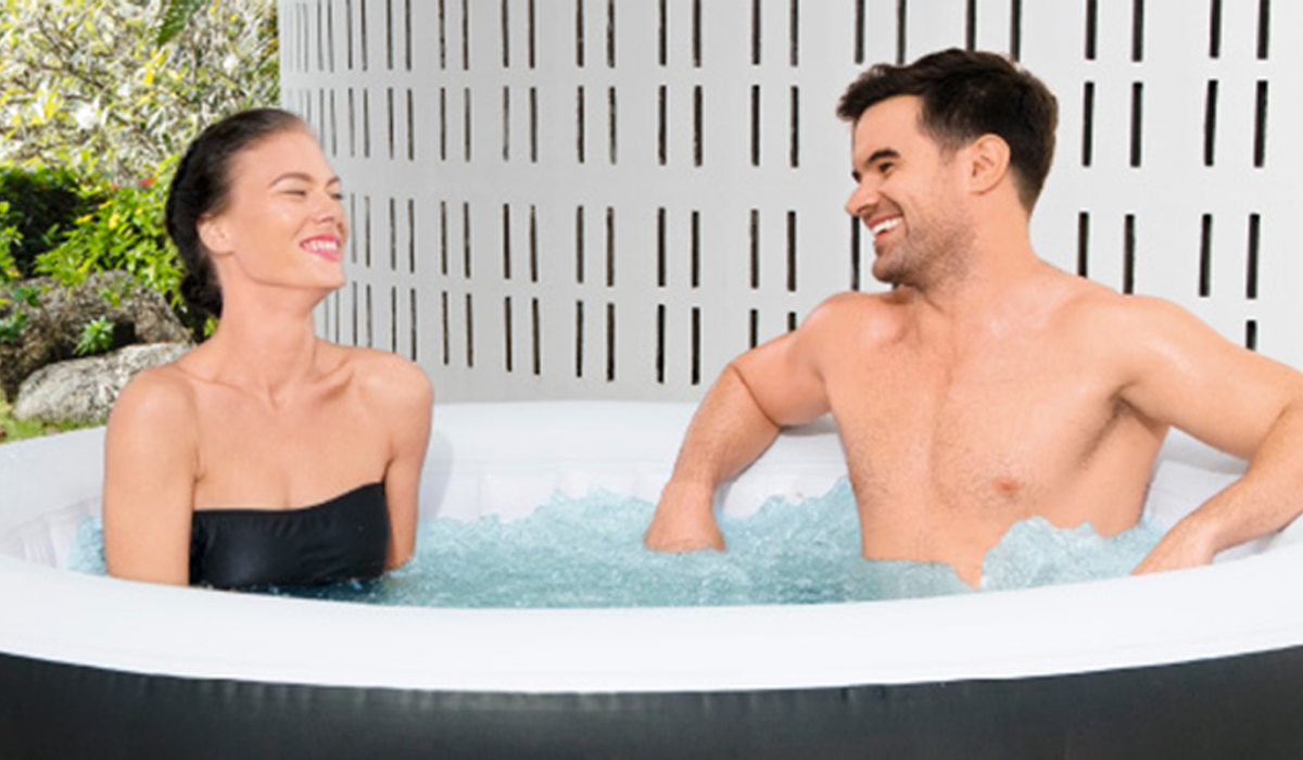 A smiling woman and man sitting in a hot tub 