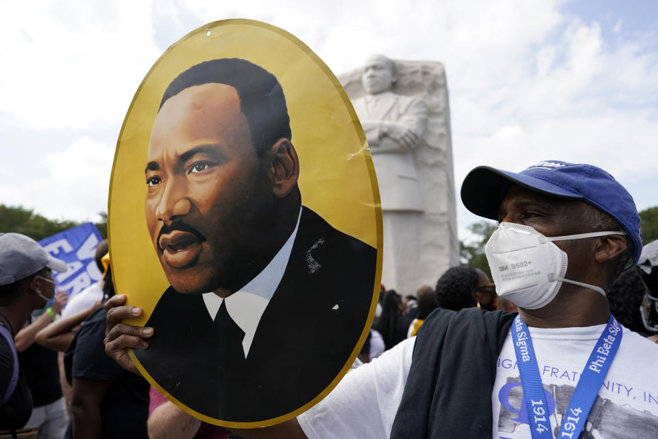 A man holds a photo of Martin Luther King, Jr., at the Martin Luther King Jr. Memorial during the March on Washington, Friday Aug. 28, 2020, in Washington. (AP Photo/Carolyn Kaster)