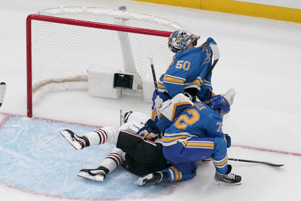 St. Louis Blues goaltender Jordan Binnington (50) tries to avoid the stick of Chicago Blackhawks' MacKenzie Entwistle as Blues Justin Faulk (72) defends during the second period of an NHL hockey game Saturday, Dec. 23, 2023, in St. Louis. (AP Photo/Jeff Roberson)