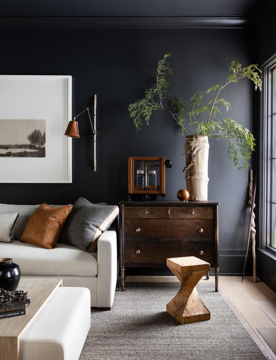 <p> When we think of neutral room ideas it's often light beige, cream and white schemes that come to mind, but the neutral palette does in fact span a huge spectrum right through to dark hues like black and charcoal. Opting for <a href="https://www.homesandgardens.com/ideas/living-room-wall-ideas" rel="nofollow noopener" target="_blank" data-ylk="slk:living room walls;elm:context_link;itc:0;sec:content-canvas" class="link ">living room walls</a> in a dark grey shade and furnishing in lighter tones and warm accents can make a beautiful twist on a classic neutral room idea as demonstrated in this space by Sean Anderson. </p> <p> While dark grey room and black room ideas can seem daunting, black and charcoal can make fantastic colors for a living room, helping to bring a cozy and cocooning feel. To make sure the look remains warm and cozy, add in plenty of rich, warm tones and rustic textures.  </p> <p> Here, a woven living room rug in grey-beige brings essential softness while the rich chestnut and tan tones of the wooden furniture, wall lighting and cushion bring warmth.  </p>