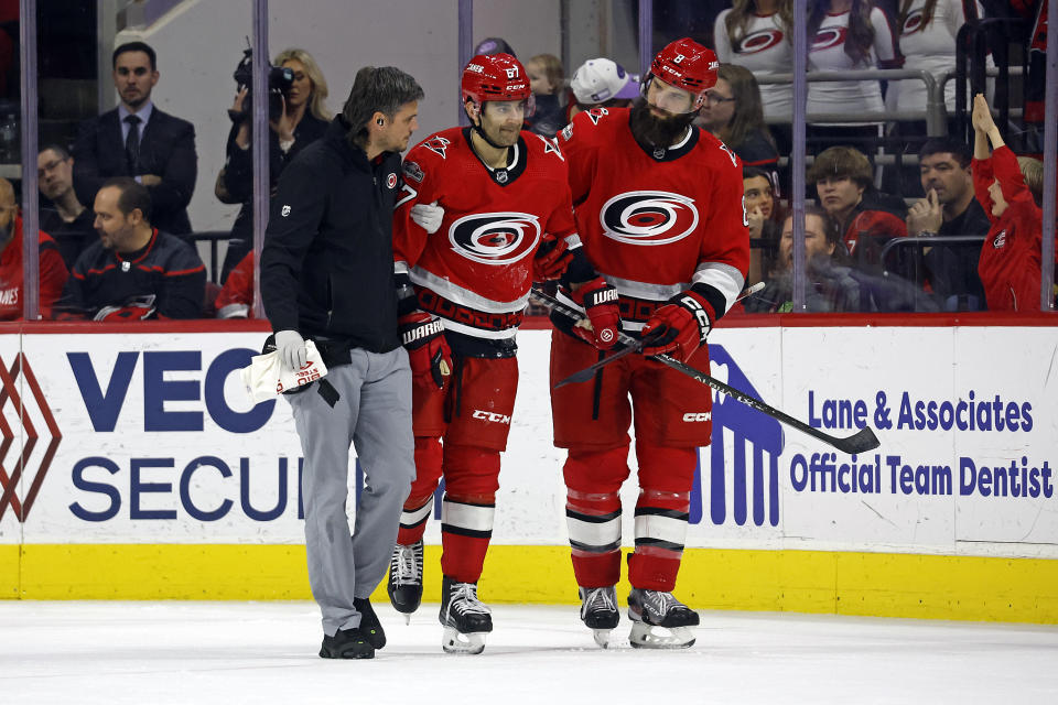 Carolina Hurricanes head athletic trainer Doug Bennett, left, and Brent Burns, right, assist Max Pacioretty off the ice following an injury during the third period of the team's NHL hockey game against the Minnesota Wild in Raleigh, N.C., Thursday, Jan. 19, 2023. (AP Photo/Karl B DeBlaker)