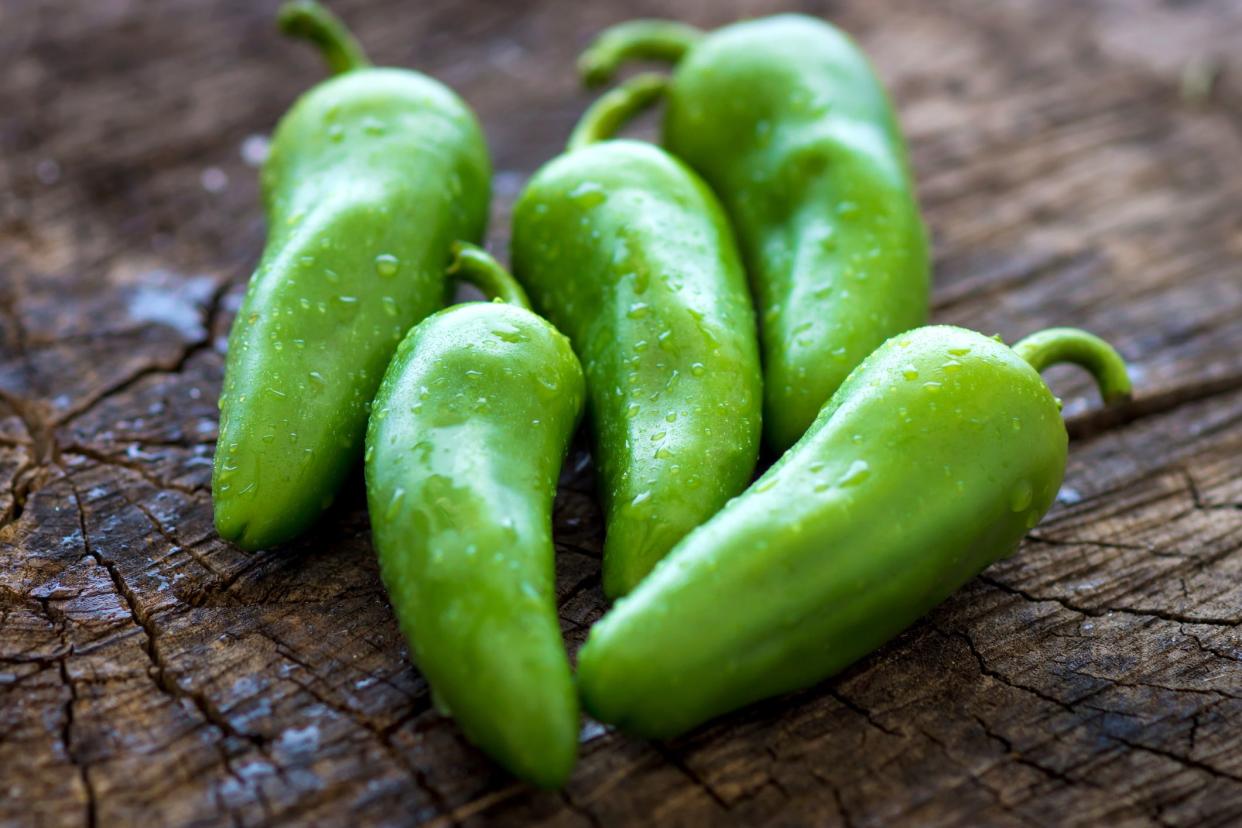 Closeup of five jalapeño peppers on a wooden table blurred background