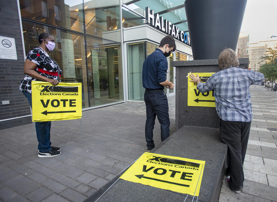 Elections Canada workers place signage at the Halifax Convention Centre as they prepare for the polls to open in the federal election in Halifax on Monday, Sept. 20, 2021. (Andrew Vaughan/The Canadian Press via AP)