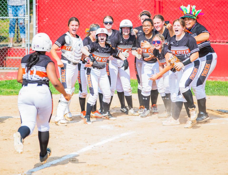 Jada Mcalmont of the Fern Creek Tigers scores a run as her teammates cheer her on at the home plate during a high school softball game between Fern Creek and Bullitt East at Bullitt East High School in Mount Washington, Kentucky on May 21, 2022.