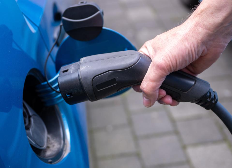 A hand plugging in an EV charger