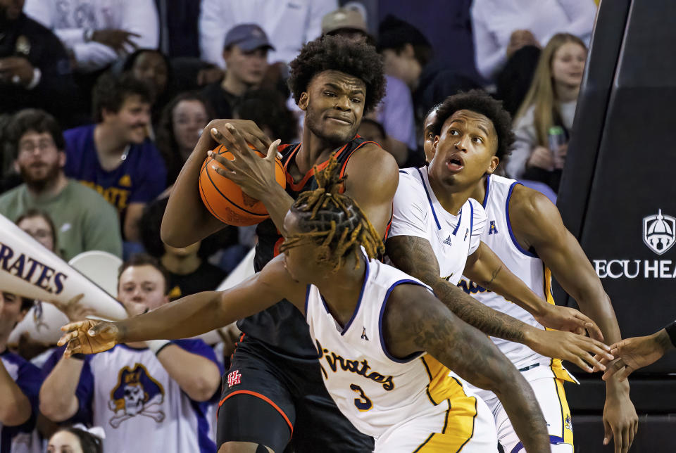 Houston's Jarace Walker tries to keep the ball from East Carolina's RJ Felton (3) and Brandon Johnson, right, during an NCAA college basketball game in Greenville, N.C., Saturday, Feb. 25, 2023. (AP Photo/Ben McKeown)