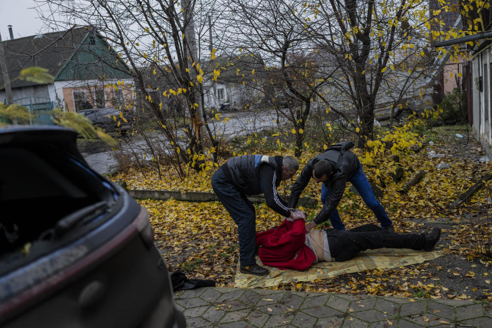City workers collect the body of a woman in Kherson, southern Ukraine, Friday, Nov. 25, 2022. The woman died during a Russian attack on Thursday. (AP Photo/Bernat Armangue)