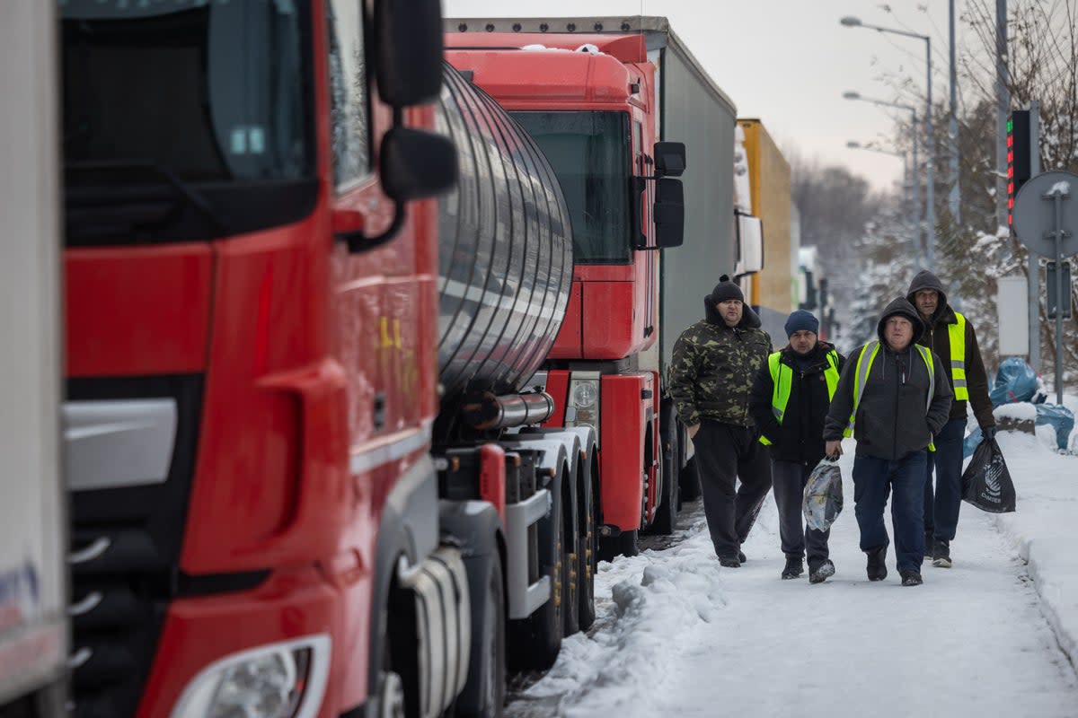 Ukrainian truck drivers walks past Ukrainian trucks as they carry bags full of groceries, on the parking lot near Korczowa Polish-Ukrainian border crossing (AFP via Getty Images)