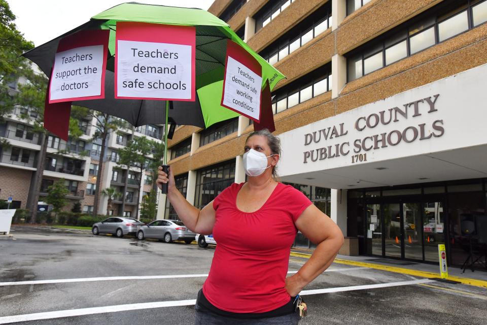 Christine O'Riley, a school teacher and the mother of a child under 12 holds her protest umbrella outside the school board building ahead of their Tuesday evening meeting to discuss the masking issue in 2021.