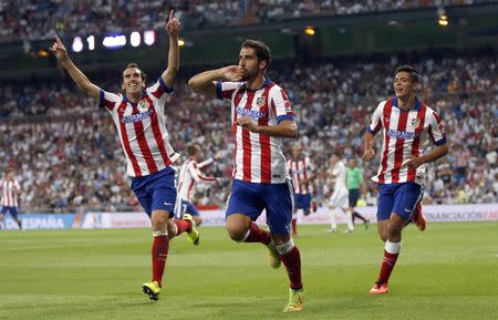 Atletico Madrid's Raul Garcia (C) celebrates beside team mates Diego Godin (L) and Raul Jimenez after scoring a goal against Real Madrid during their Spanish Super Cup first leg soccer match at Santiago Bernabeu stadium in Madrid August 20, 2014. REUTERS/Sergio Perez