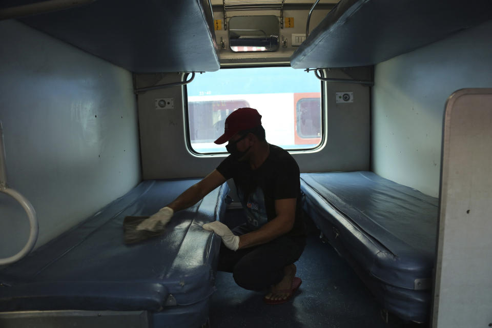 An Indian worker disinfects a train coach as a precaution against COVID-19 in Jammu, India, Tuesday, March 17, 2020. For most people, the new coronavirus causes only mild or moderate symptoms. For some it can cause more severe illness. (AP Photo/Channi Anand)