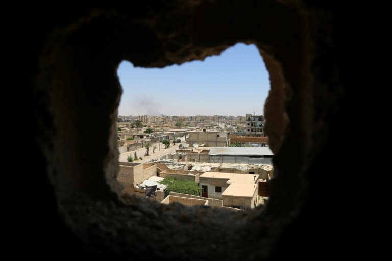 A general view shows areas under Islamic State group control in Raqa, through a hole in the wall of a building in the suburb of Dariya, on June 27, 2017