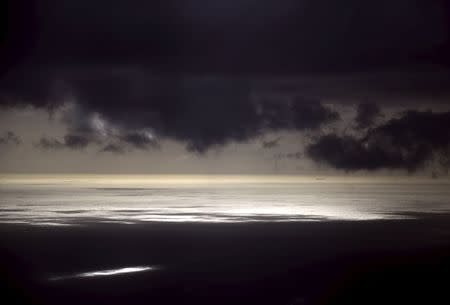 Storm clouds can be seen above a coal ship as it sails near Lady Elliot Island located north-east of the town of Bundaberg in Queensland, Australia, June 9, 2015. REUTERS/David Gray