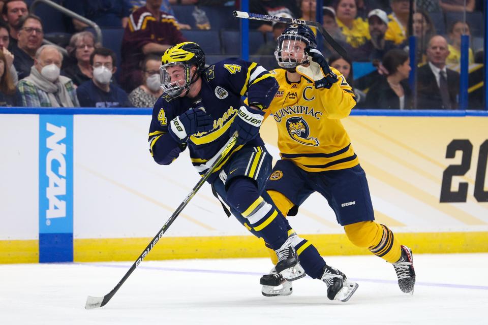 Michigan forward Gavin Brindley (4) and Quinnipiac defenseman Zach Metsa (23) battle fro the puck during the first period in the semifinals of the 2023 Frozen Four at Amalie Arena in Tampa, Florida, on Thursday, April 6, 2023.