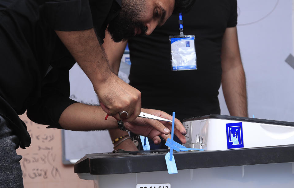 An election worker opens a ballot box after the polls closed in Baghdad, Iraq, Sunday, Oct. 10, 2021. Polls have closed across Iraq Sunday evening in parliamentary elections that were held months ahead of schedule in response to a popular uprising against corruption and mismanagement. (AP Photo/Hadi Mizban)