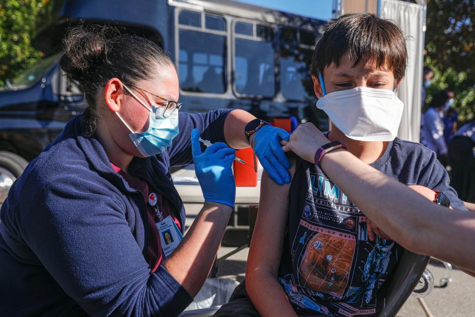 Medical assistant Maria Solis, left, gives Lief Ramirez (11), right his first dose of a COVID-19 vaccine at a mobile clinic in Austin, Texas on Nov. 11, 2021. Ramirez's said his advice to other children and adults was "Just get it and don't be worried. It hurts a little bit, but it's better than gatting COVID."