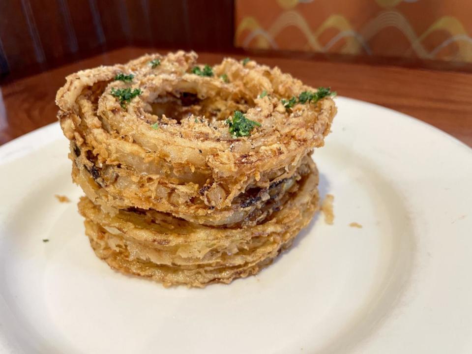 A half onion ring loaf sits on a white plate.