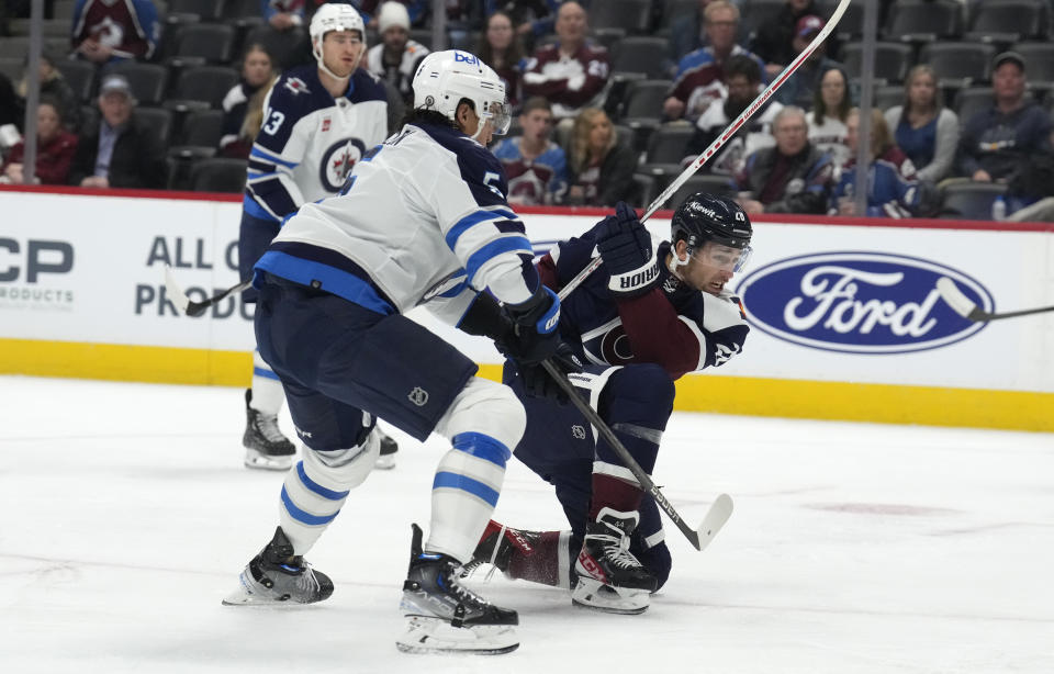 Colorado Avalanche left wing Miles Wood, right, shoots the puck next to Winnipeg Jets defenseman Brenden Dillon during the first period of an NHL hockey game Thursday, Dec. 7, 2023, in Denver. (AP Photo/David Zalubowski)