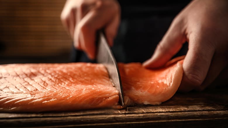 hands cutting salmon