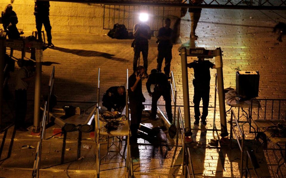 Israeli police officers dismantle metal detectors outside the al-Aqsa mosque - Credit: Mahmoud Illean/AP