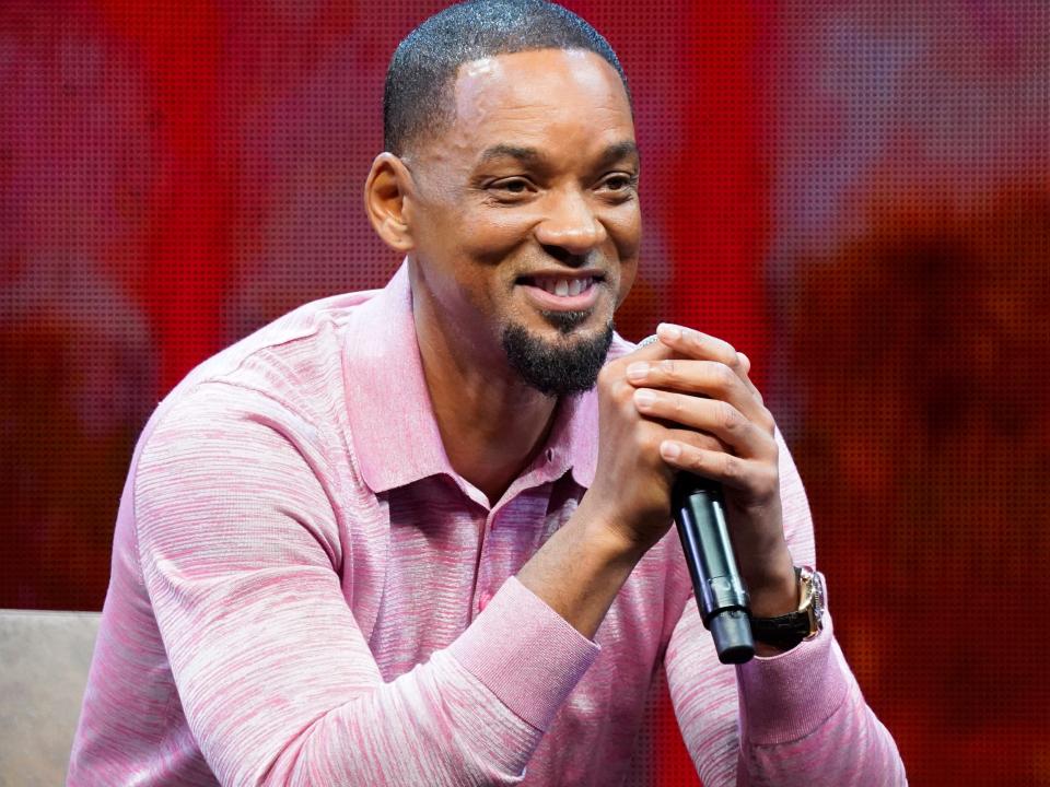 Will Smith wearing a pink shirt and holding a microphone during an interview.