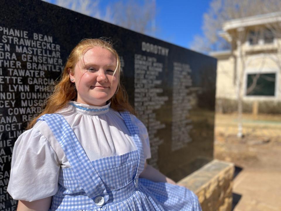 One of the museum's Dorothy Gale tour guides stands in front of a monument etched with the names of the many Dorothys who have come before her at the Land of Oz in Liberal.