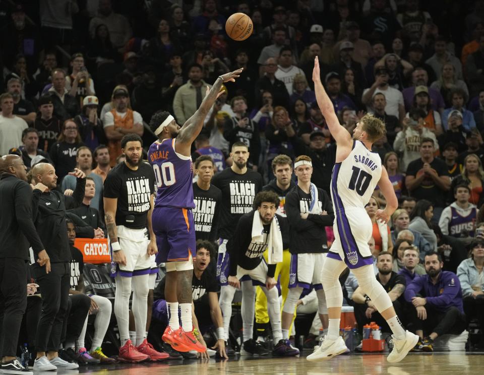 Phoenix Suns forward Royce O'Neale (00) shoots a three-point basket against Sacramento Kings forward Domantas Sabonis (10) during the fourth quarter of a game at Footprint Center in Phoenix on Feb. 13, 2024.