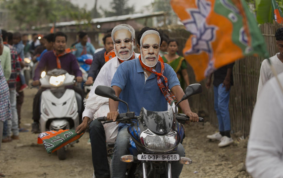 FILE - In this April 2, 2019 file photo, Bharatiya Janata Party (BJP) supporters wear masks of Indian Prime Minister Narendra Modi and ride a motorbike during an election campaign rally ahead of general elections in Borhola village, Assam state, India. The final phase of India’s marathon general election will be held on Sunday, May 19. The first of the election’s seven staggered phases was held on April 11. Vote counting is scheduled to start on May 23. India has 900 million eligible voters. (AP Photo/Anupam Nath, File)