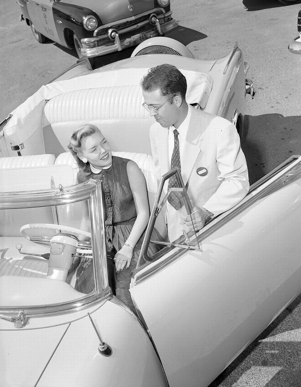 June 13, 1953: Paul Leonard, one of the owners of Leonard’s Department Store, and Miss Pat Godby, advertising artist at the store, look over the Packard convertible that will be given away at the store in a contest starting Monday.