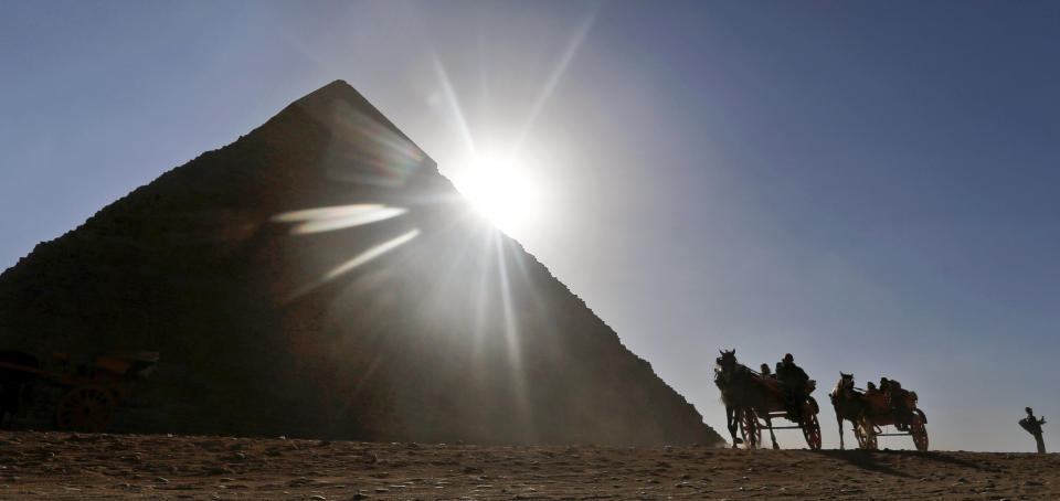 FILE - In this Wednesday, Dec. 12, 2012 file photo, Tourists ride in horse carriages past one of the Great Pyramids in Giza, Egypt. The past month saw a drop in tourists to Egypt, scared off by scenes of protests and clashes over the constitution, in new pain to a crucial industry gutted the past two years by turmoil. Tourism workers worry things won’t get any better even now that the charter has been passed: Egypt’s power struggles threaten to erupt into more unrest at any time, and some fear Islamists will eventually try to rein in alcohol and beach tourism. (AP Photo/Petr David Josek, File)