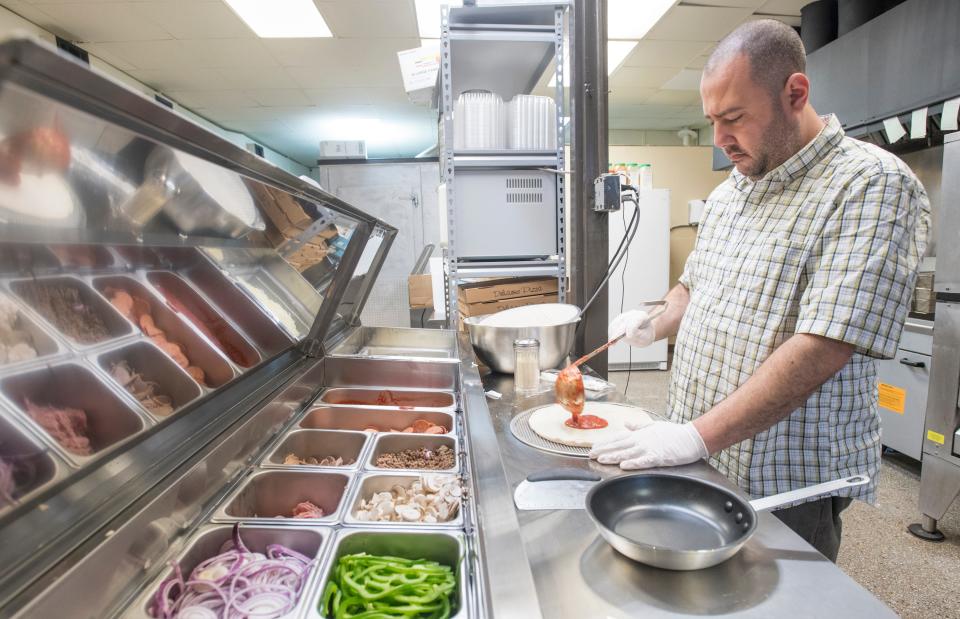 Co-owner Rami Rian adds sauce to a pizza at Pizza Kitchen on Ninth Avenue in Pensacola on Friday, Jan. 10, 2020.